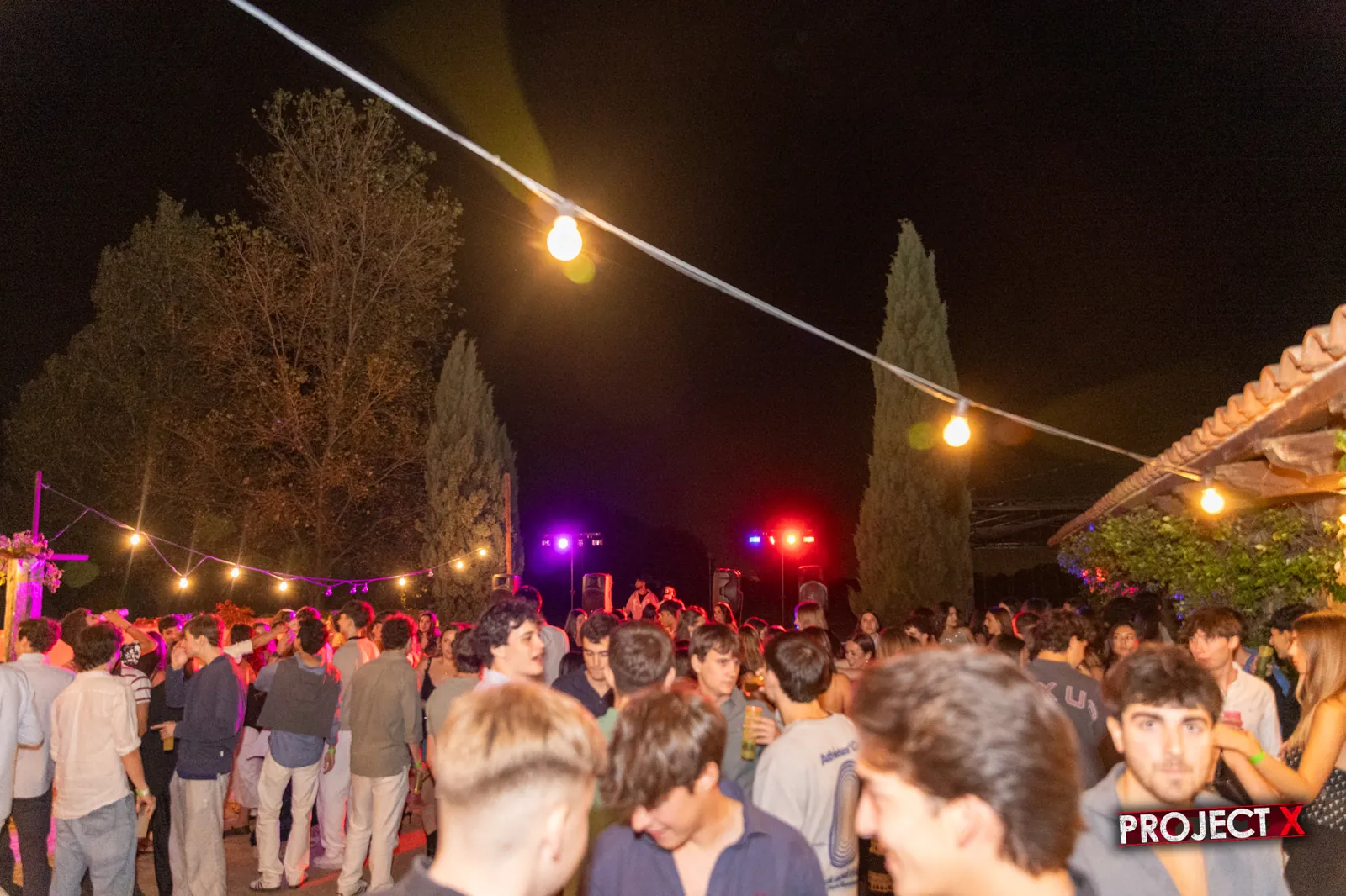 La pista exterior de la finca llena, de noche, con guirnaldas de luces